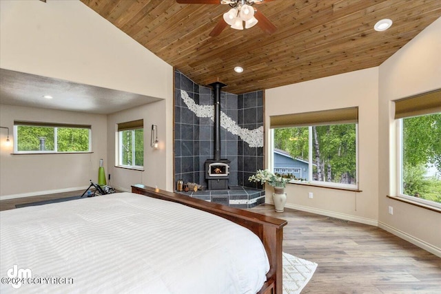 bedroom with lofted ceiling, wood ceiling, hardwood / wood-style flooring, and a wood stove