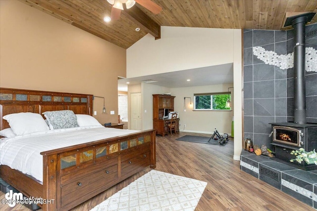 bedroom with beamed ceiling, a wood stove, hardwood / wood-style floors, and wooden ceiling