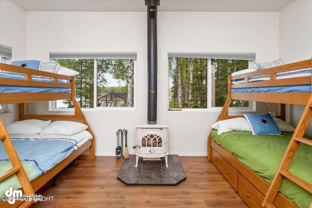 bedroom with hardwood / wood-style flooring and a wood stove