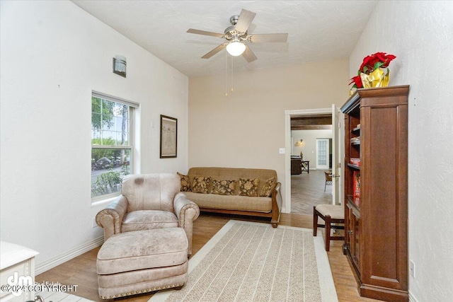 living room featuring ceiling fan, wood-type flooring, and a textured ceiling