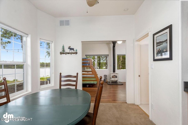 carpeted dining room with a healthy amount of sunlight and a wood stove