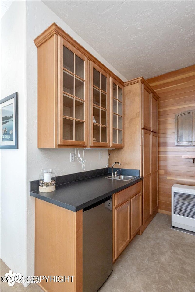 kitchen featuring wooden walls, dishwasher, sink, and heating unit