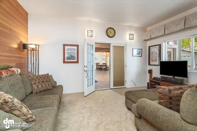 carpeted living room with french doors and wooden walls