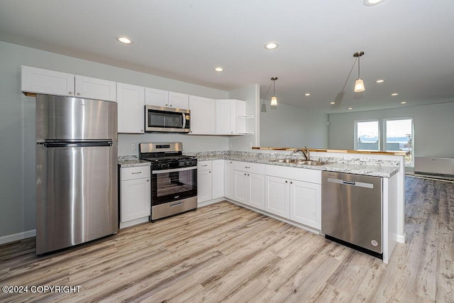 kitchen featuring light stone counters, decorative light fixtures, white cabinets, appliances with stainless steel finishes, and sink