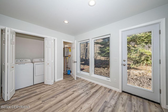 laundry area featuring washing machine and dryer, light wood-type flooring, and water heater