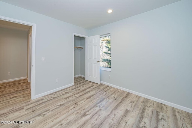 unfurnished bedroom with light hardwood / wood-style flooring and a closet