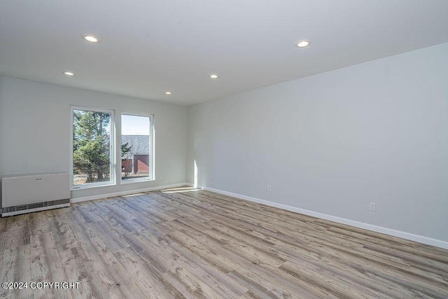 empty room with light wood-type flooring and heating unit