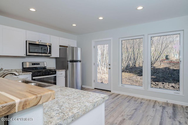 kitchen featuring sink, white cabinets, light wood-type flooring, and appliances with stainless steel finishes