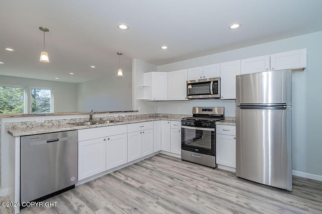 kitchen with light stone countertops, hanging light fixtures, white cabinets, appliances with stainless steel finishes, and sink