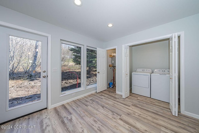 clothes washing area with independent washer and dryer and light hardwood / wood-style floors