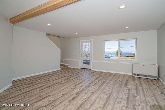 unfurnished living room featuring light hardwood / wood-style flooring, beamed ceiling, and heating unit