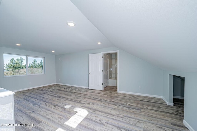 bonus room with light wood-type flooring and vaulted ceiling