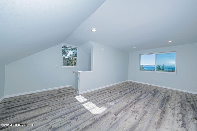 bonus room with a healthy amount of sunlight, light wood-type flooring, and lofted ceiling