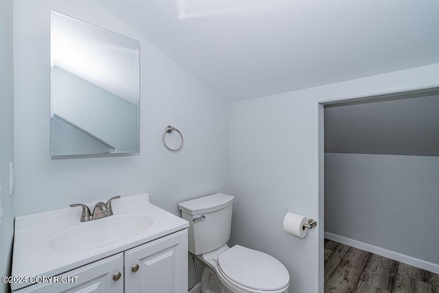 bathroom with lofted ceiling, toilet, vanity, and wood-type flooring