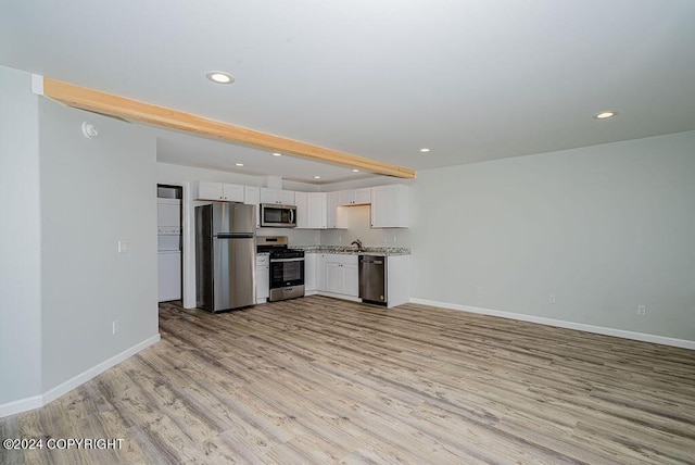 kitchen with light hardwood / wood-style floors, stainless steel appliances, light stone counters, beam ceiling, and white cabinets