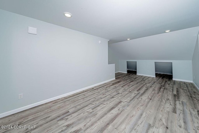 additional living space with vaulted ceiling and light hardwood / wood-style flooring