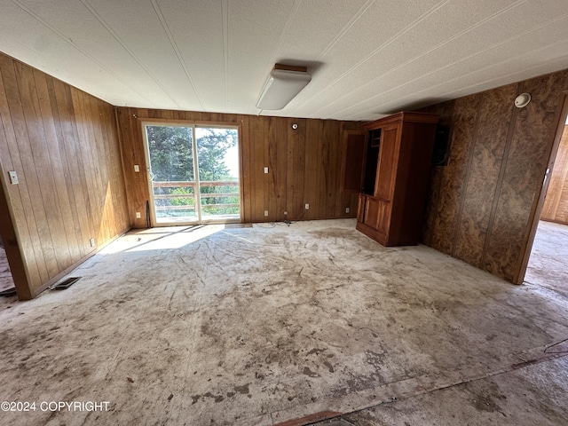 carpeted spare room with wood walls