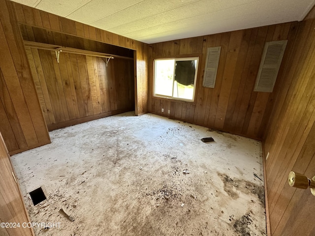 unfurnished bedroom with a closet and wood walls