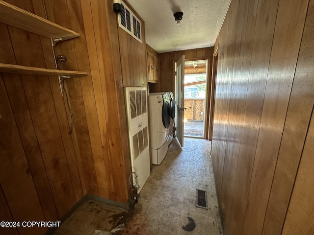 laundry area featuring independent washer and dryer, a textured ceiling, cabinets, and wooden walls