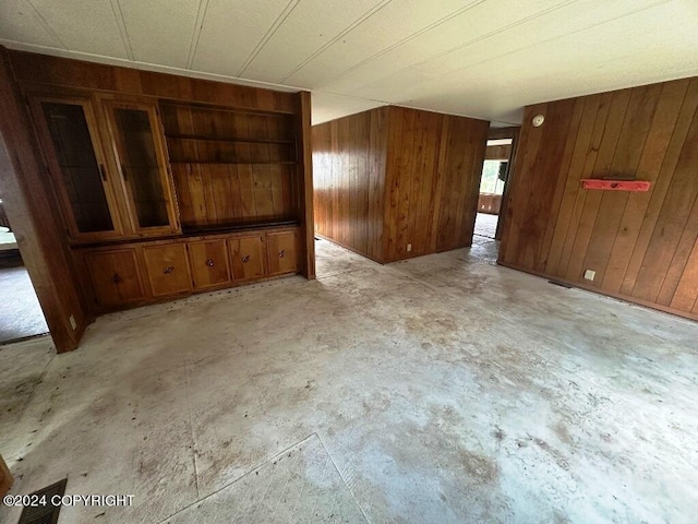 unfurnished living room featuring wooden walls