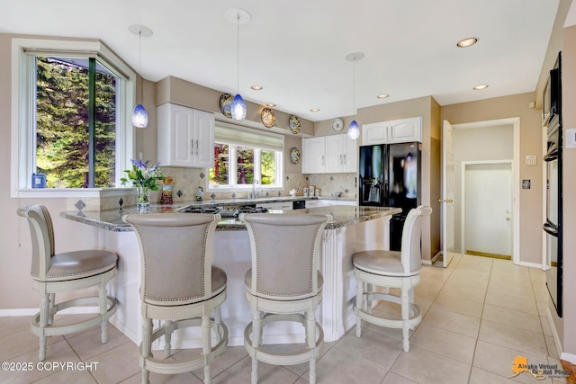 18706 Petrel Cir, Anchorage, AK 99516 - kitchen featuring black appliances, stone countertops, tasteful backsplash, a peninsula, and recessed lighting