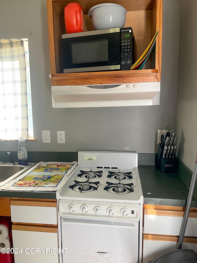 kitchen featuring white gas range and exhaust hood