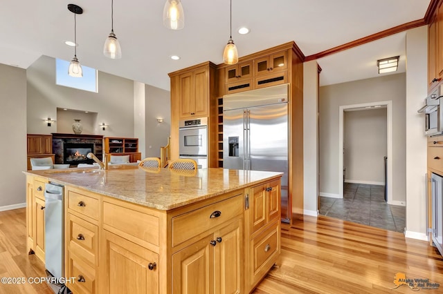 16268 Noble Point Dr, Anchorage, AK 99516 - kitchen with stainless steel appliances, a glass covered fireplace, light wood-style flooring, light stone countertops, and recessed lighting