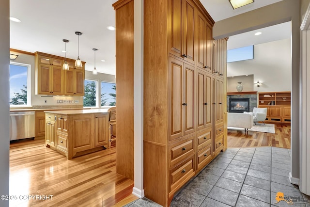 16268 Noble Point Dr, Anchorage, AK 99516 - kitchen featuring stainless steel dishwasher, light countertops, light wood-type flooring, a glass covered fireplace, and recessed lighting