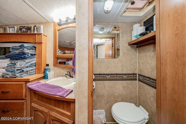 bathroom featuring vanity, toilet, and tile walls