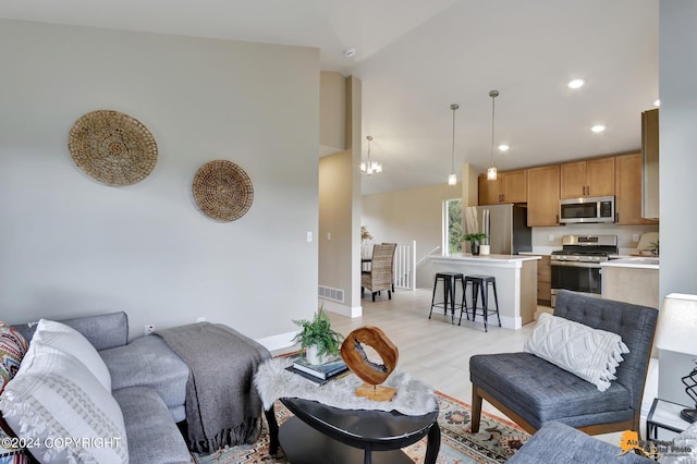 living room featuring vaulted ceiling, light hardwood / wood-style flooring, and a notable chandelier