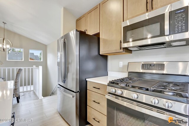 kitchen with light brown cabinetry, appliances with stainless steel finishes, hanging light fixtures, a chandelier, and lofted ceiling