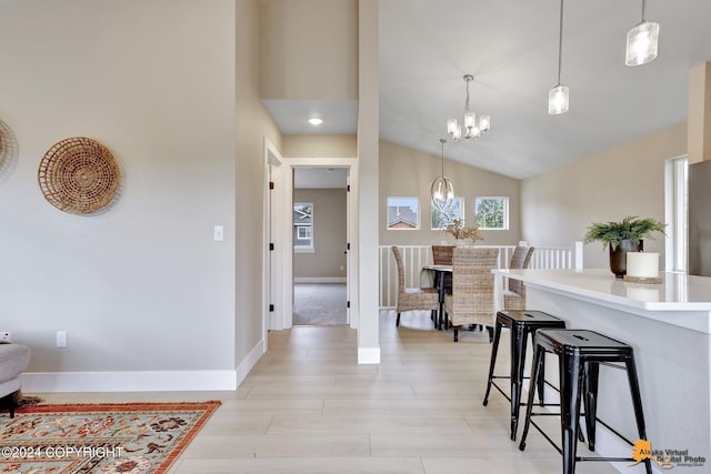 kitchen featuring lofted ceiling, pendant lighting, an inviting chandelier, and a kitchen breakfast bar