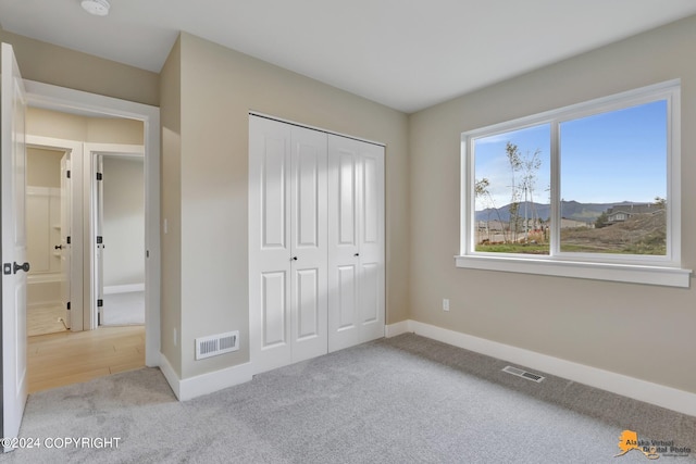 unfurnished bedroom featuring a closet and light carpet