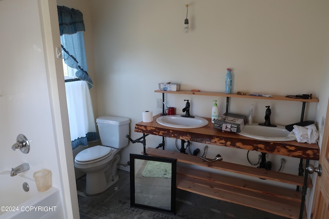 bathroom featuring dual sinks and toilet