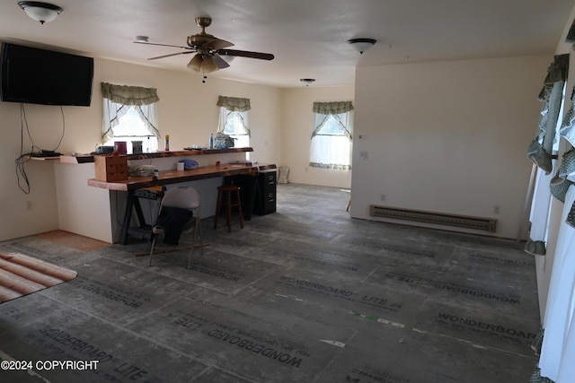 interior space featuring a kitchen breakfast bar, ceiling fan, plenty of natural light, and a baseboard heating unit