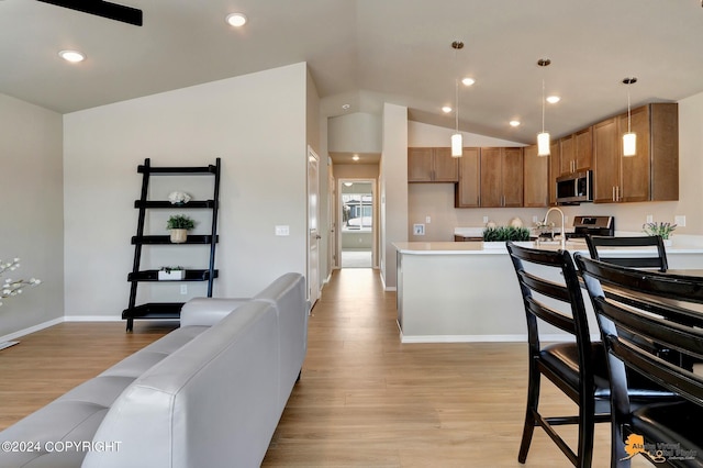 kitchen featuring vaulted ceiling, appliances with stainless steel finishes, light hardwood / wood-style flooring, and decorative light fixtures