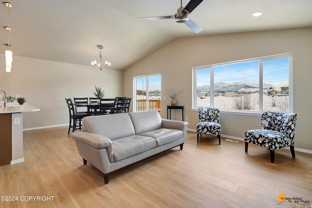 living room featuring a mountain view, plenty of natural light, light hardwood / wood-style floors, and ceiling fan with notable chandelier