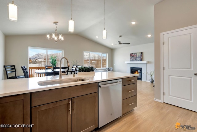 kitchen with stainless steel dishwasher, sink, a tile fireplace, and decorative light fixtures