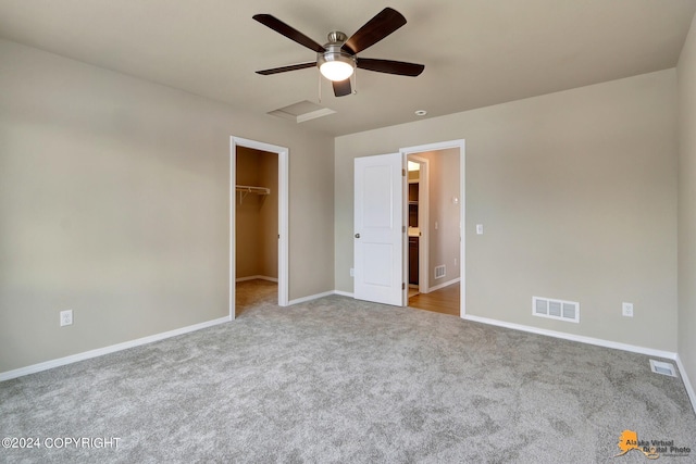 unfurnished bedroom featuring a spacious closet, ceiling fan, a closet, and light colored carpet