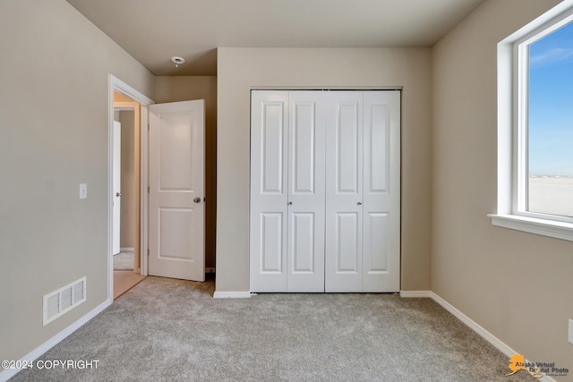 unfurnished bedroom featuring light colored carpet and a closet