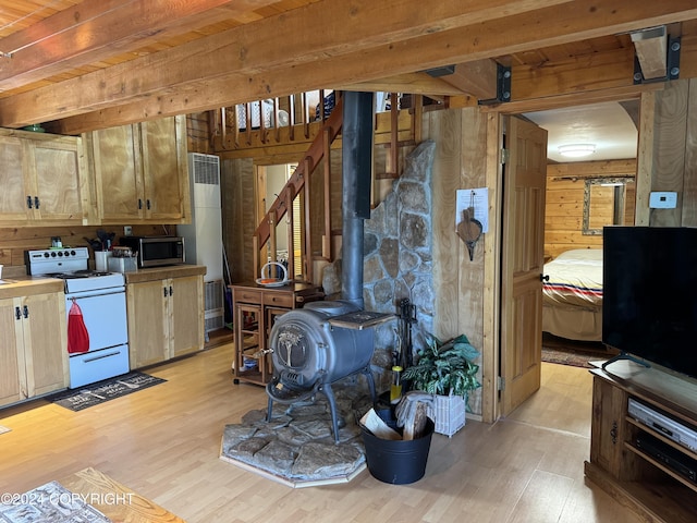 34335 Keystone Dr, Soldotna, AK 99669 - kitchen featuring white stove, stainless steel microwave, light wood-style flooring, a wood stove, and wooden walls