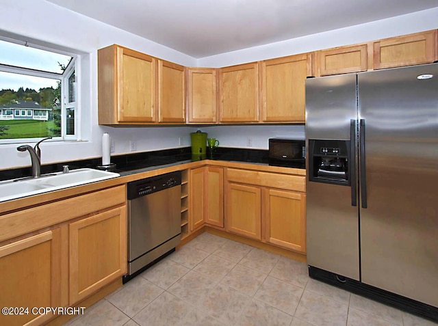 kitchen featuring a sink, dark countertops, light tile patterned floors, and stainless steel appliances