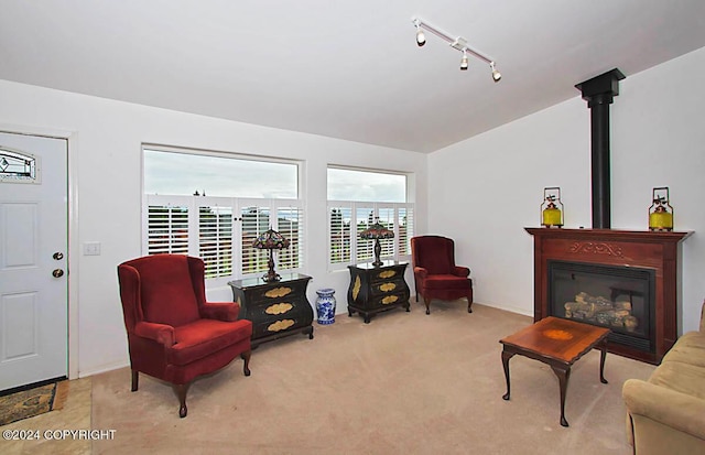 sitting room with rail lighting, a glass covered fireplace, carpet flooring, and vaulted ceiling