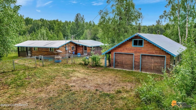 rear view of house featuring a garage, an outbuilding, and a yard