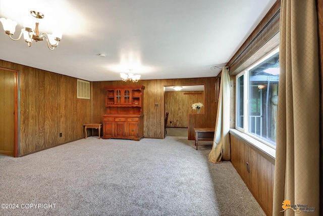 interior space featuring carpet floors, wooden walls, and a chandelier