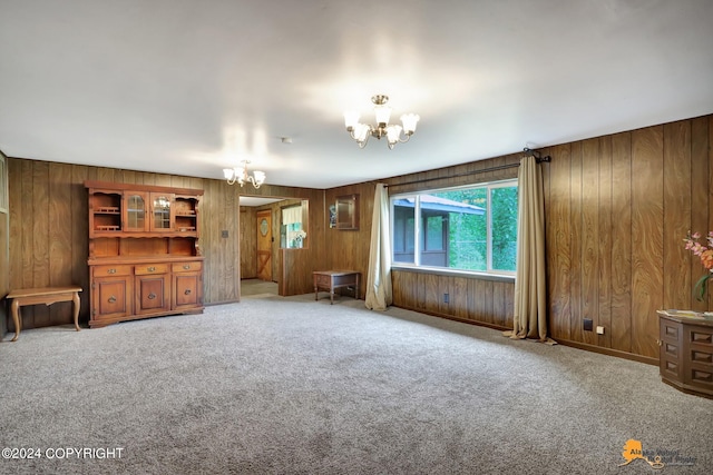 unfurnished living room with wood walls, a chandelier, and light carpet