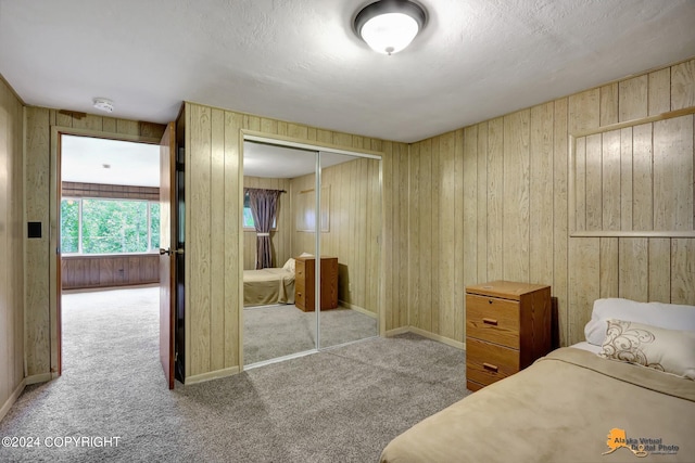 bedroom with wooden walls, light carpet, and a closet