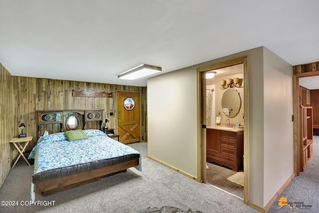 carpeted bedroom with connected bathroom and wood walls