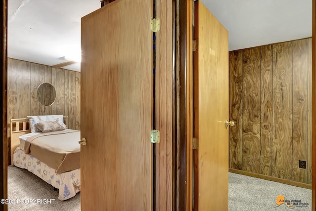 carpeted bedroom featuring wood walls