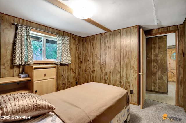 carpeted bedroom featuring beam ceiling and wood walls